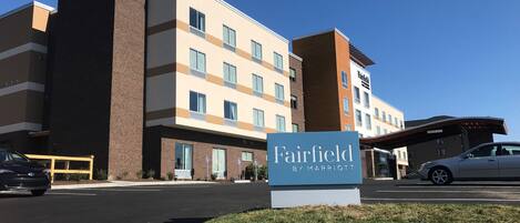 Een Fairfield by Marriott hotel met een modern design, inclusief een parkeerplaats en een helderblauwe lucht.