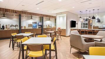 A modern cafe with wooden accents, yellow chairs, and a variety of seating options including tables and booths.