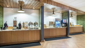 A clean, modern reception area with a wooden counter, a coffee machine, and a television screen. - Fairfield Inn & Suites by Marriott Pigeon Forge (Pigeon Forge)