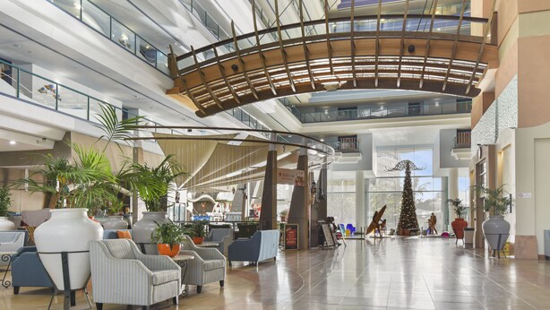 A spacious lobby with multiple seating areas, a central staircase, and a large Christmas tree.