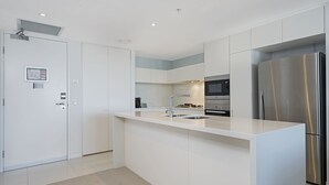 Een moderne keuken met witte kasten, roestvrijstalen apparatuur en een centraal keukenblok met een spoelbak.