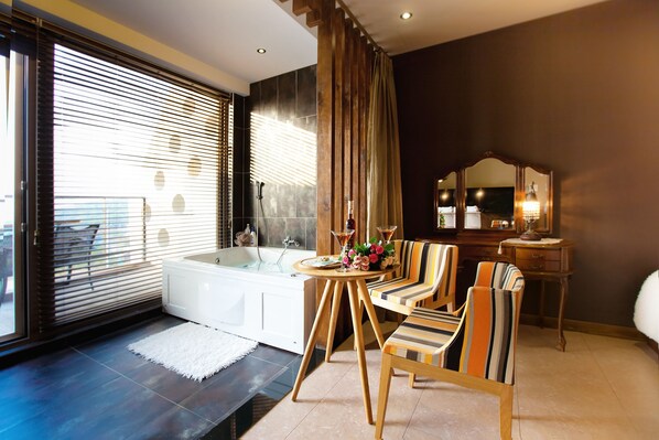 A modern bathroom with a bathtub, a vanity with a mirror, striped chairs, and a view through large windows. - Healing 11st Pension (Incheon)