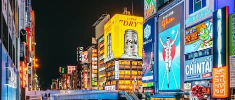 A busy urban street at night with illuminated billboards and signs.