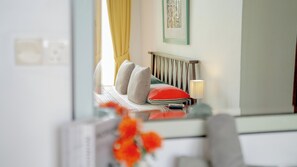 Habitación de hotel con cama, lámpara de noche, ventana con cortinas e imagen en el pared.