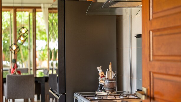 A kitchen with a stove, a sink, and a decorative figure holding a beer mug. - The Villa - Luxury Private Pool Villa (Langkawi)