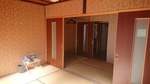Une pièce de style japonais traditionnel, avec un sol recouvert de tatamis, des portes coulissantes et une petite table agrémentée d’une poubelle.