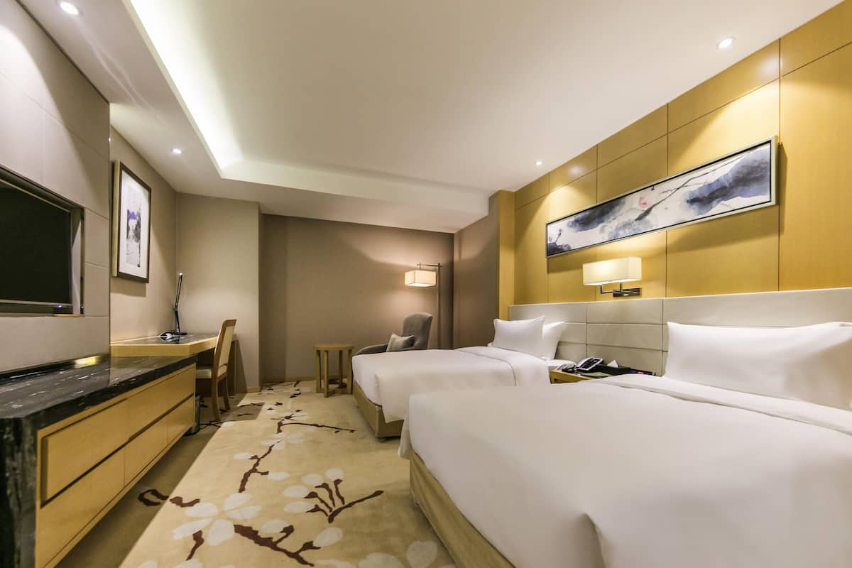 Una habitación de hotel con cama, mesita de noche, lámpara y un cuadro en la pared.