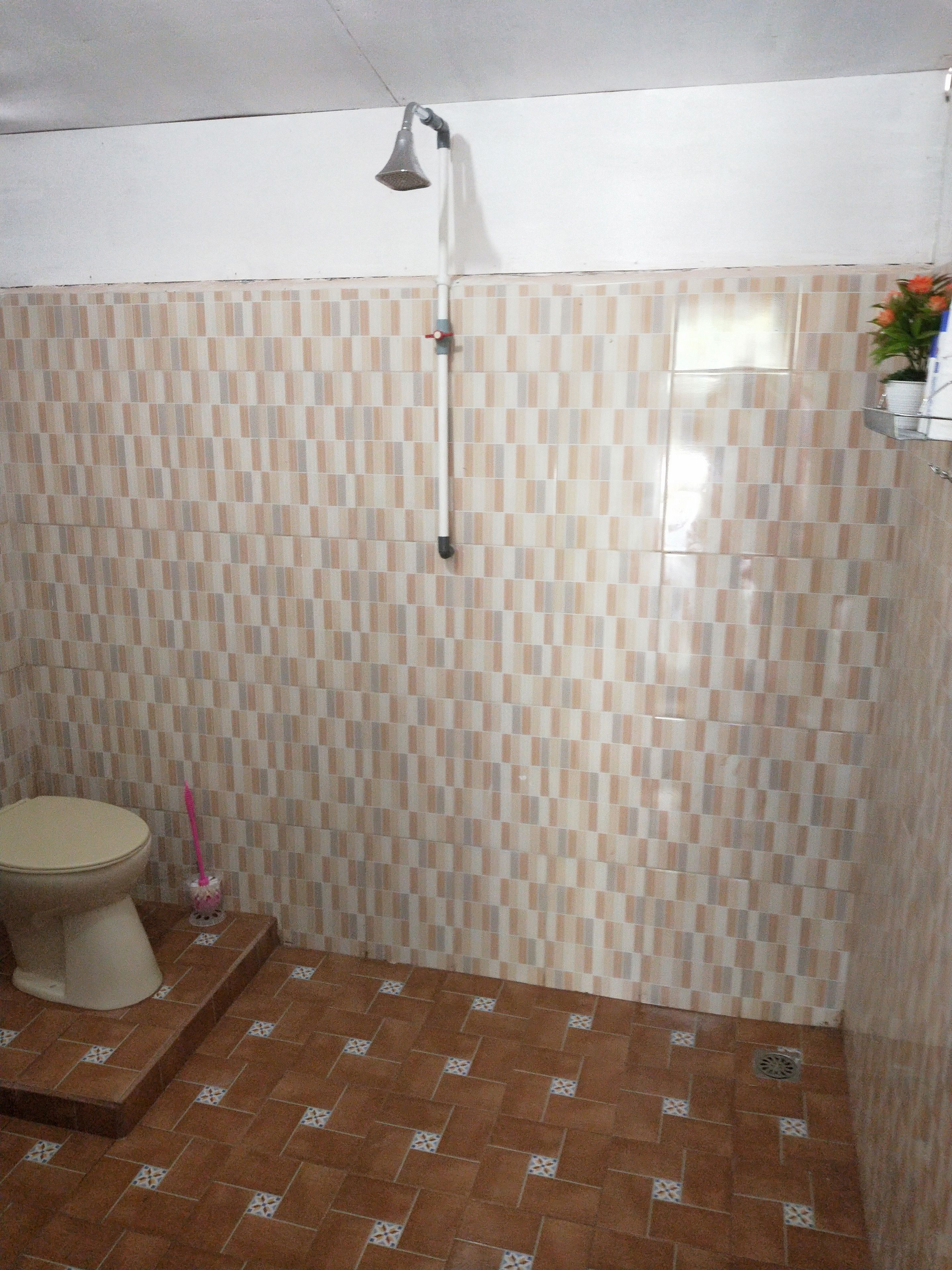 Un baño con ducha, inodoro y suelo de baldosas.
