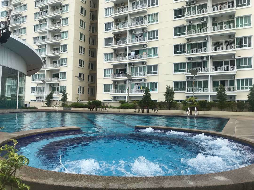 A swimming pool with a hot tub in the center, surrounded by a multi-story residential building with balconies.