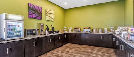 A kitchen with dark cabinets, a microwave, a coffee machine, and a refrigerator.