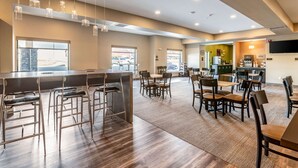 A spacious dining area with high tables and chairs, a bar area with stools, and large windows providing natural light. - Sleep Inn & Suites Mt. Hope near Auction & Event Center (Mount Hope)