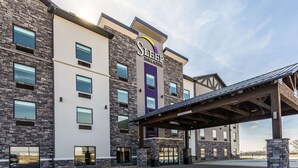 A Sleep Inn & Suites building with a modern design, featuring a mix of brick and stone facades, large windows, and a covered entrance area. - Sleep Inn & Suites Mt. Hope near Auction & Event Center (Mount Hope)
