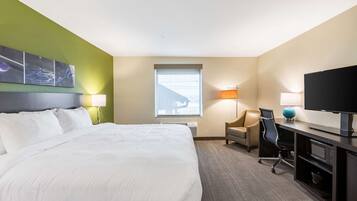 A hotel room with a large bed, a desk with a computer, a chair, and a television.
