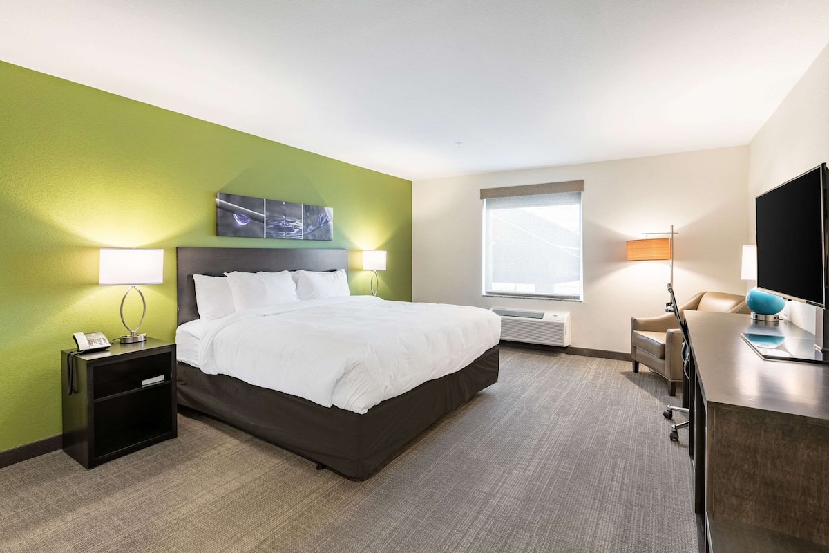 A hotel room with a bed, bedside tables, a desk, and a TV.