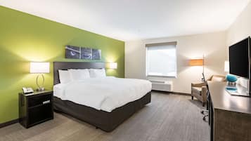 A hotel room with a bed, bedside tables, a desk, and a TV.