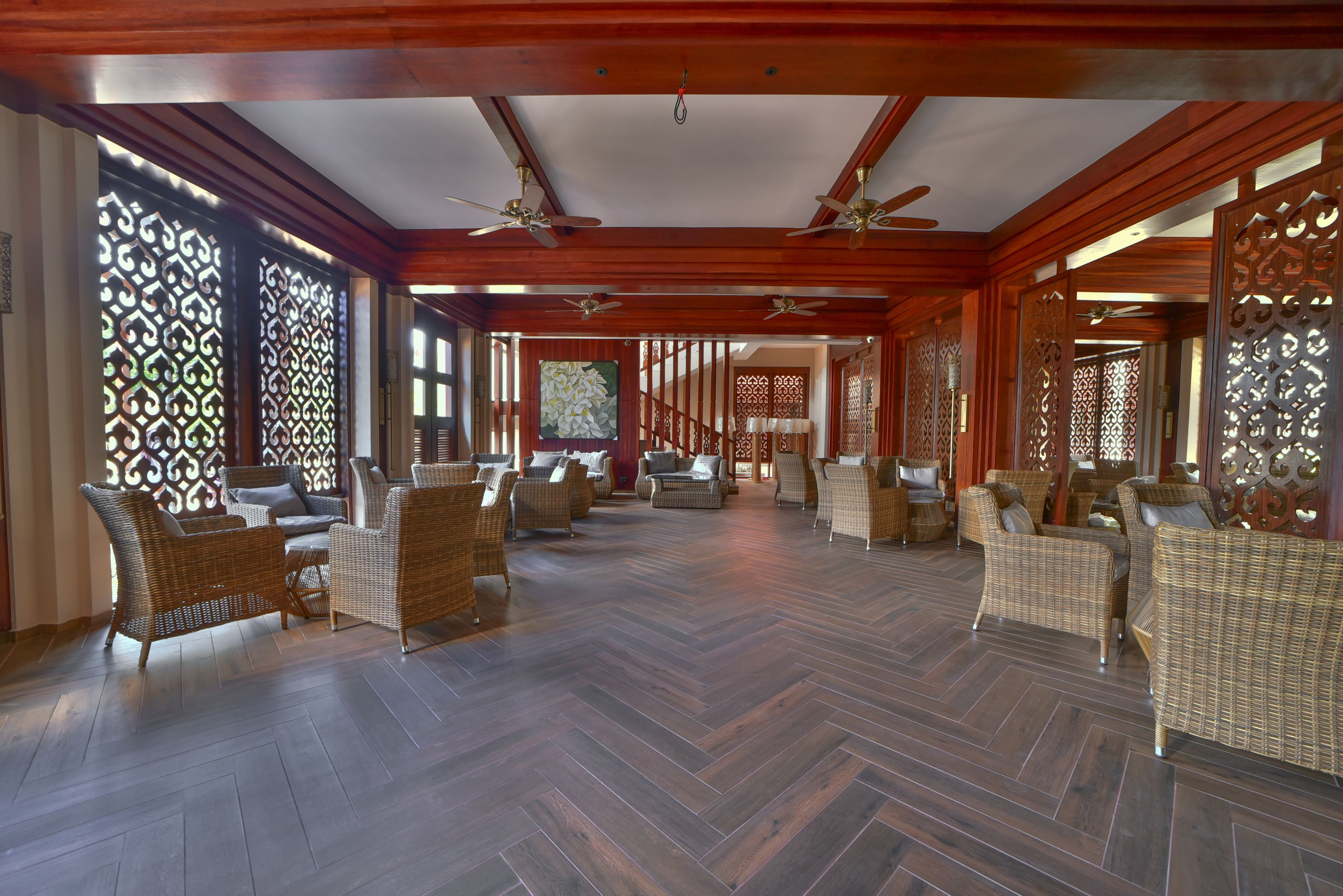 Un hall d’entrée spacieux doté de parquets en bois, de meubles en osier et de paravents décoratifs.