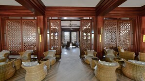 A traditional room with wooden partitions, wicker furniture, and a herringbone floor. - Sea Shell Samssara (Port Blair)