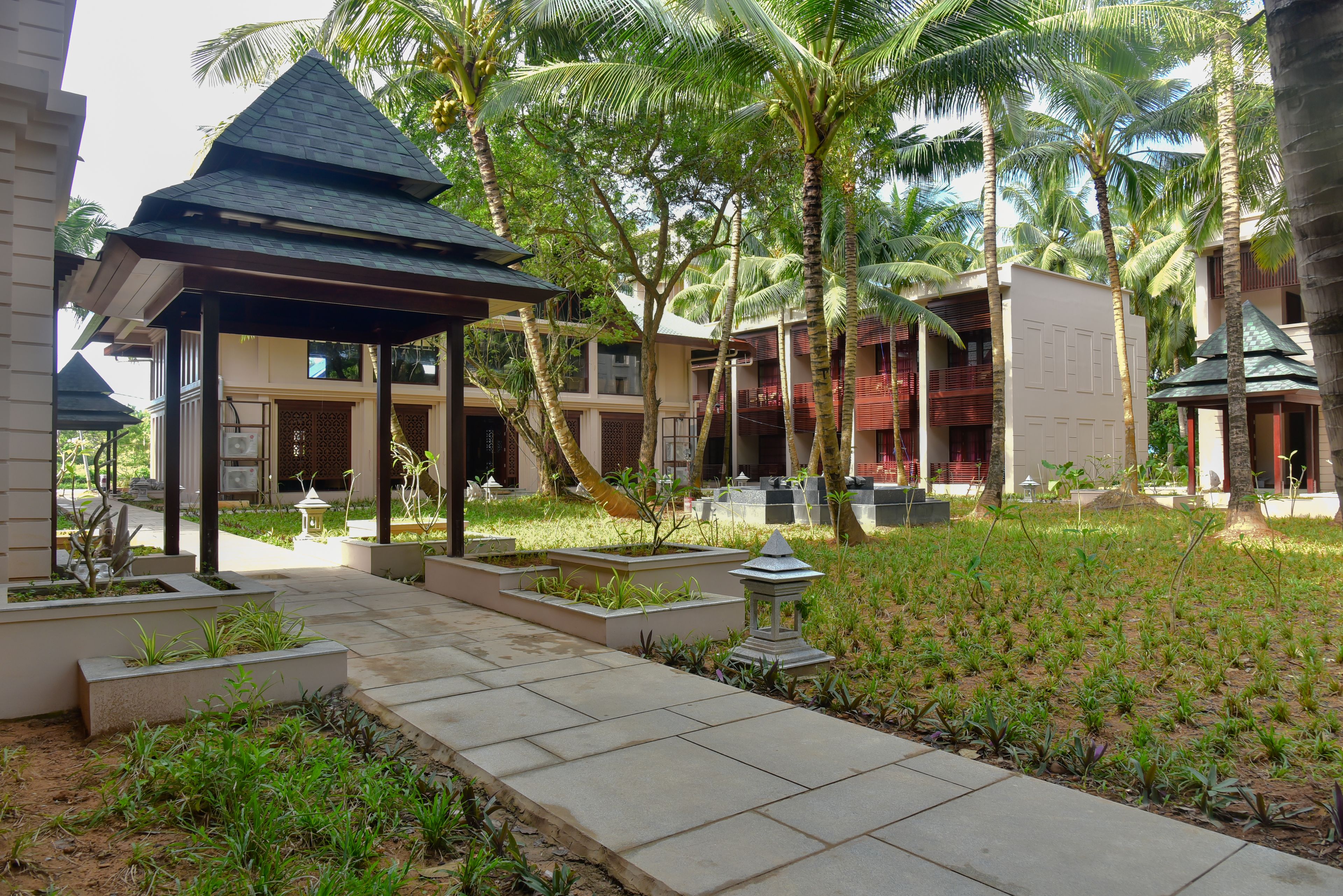 A resort with a covered walkway, palm trees, and a well-maintained garden.