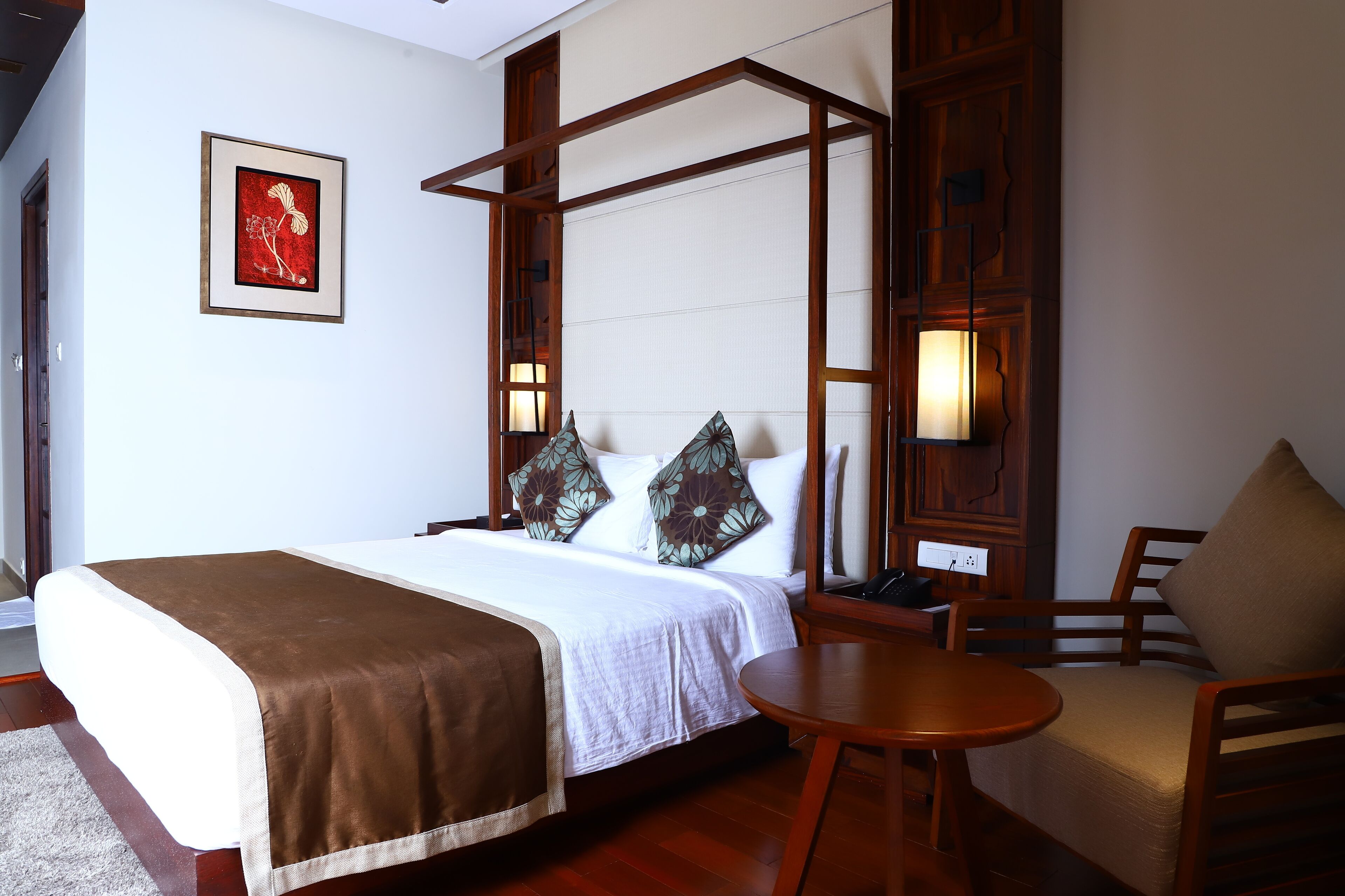 A neatly arranged hotel room with a bed, bedside table, and a chair.