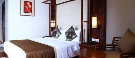 A neatly arranged hotel room with a bed, bedside table, and a chair.