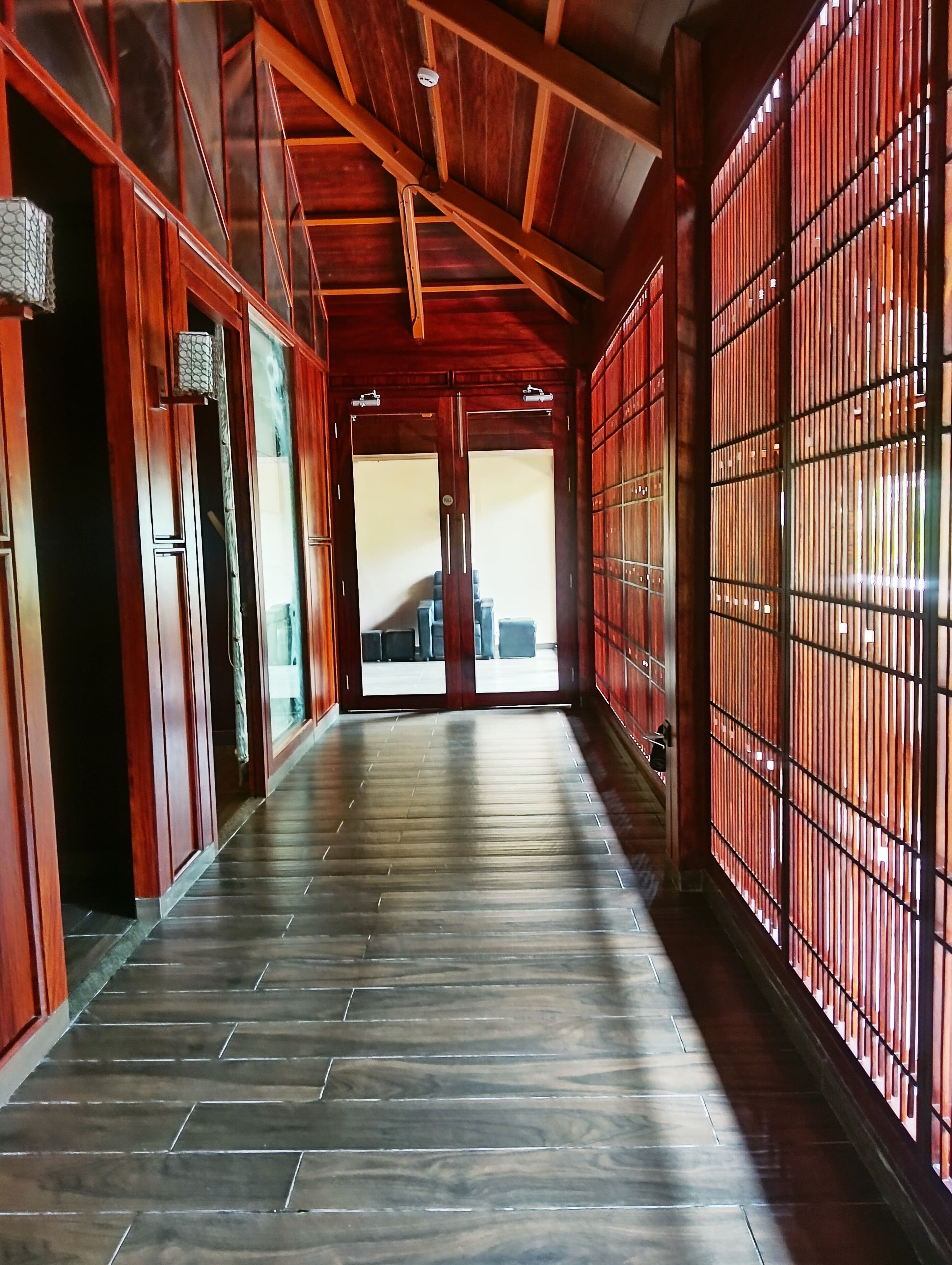 A corridor with wooden flooring and walls, leading to a room with a view.