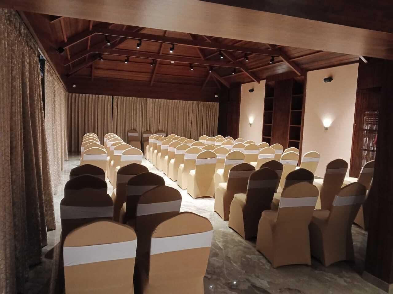 A conference room with rows of chairs, a stage, and a wooden ceiling.