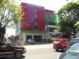 Un edificio de varios pisos con un cartel llamativo que dice "MANADO INN".