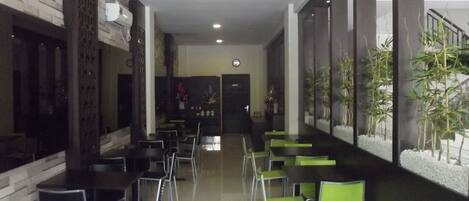 A modern indoor dining area with tables and chairs, a staircase, and decorative plants.