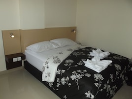 Una cama bien hecha con una colcha floral blanco y negro y almohadas blancas.