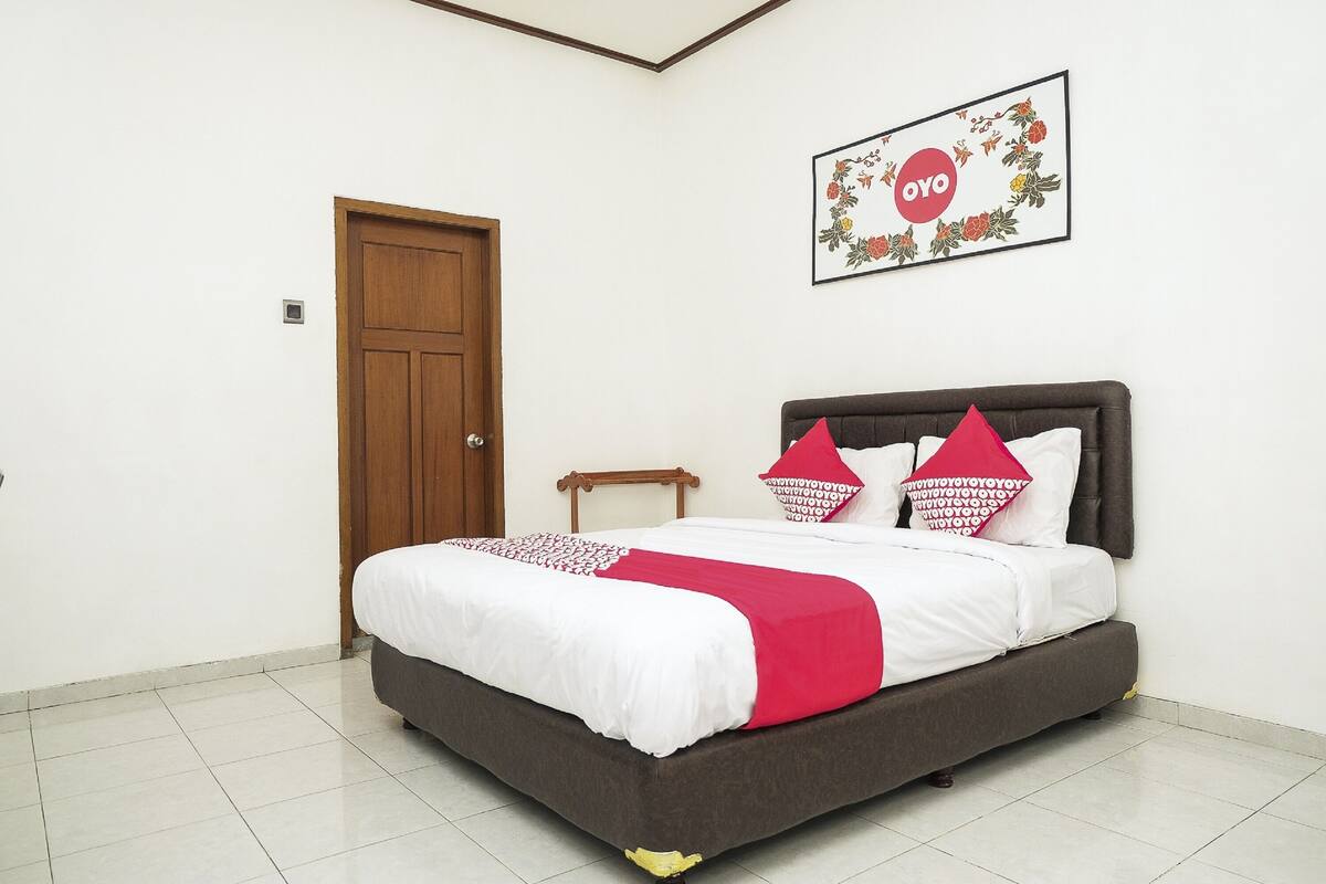 A neatly made bed with a white and red bedspread, a wooden headboard, and matching pillows.
