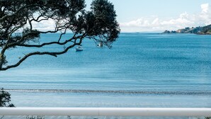 A coastal view with a boat on the water, trees, and a clear sky.