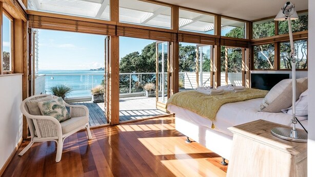 A spacious bedroom with a large window overlooking a balcony and a scenic view.