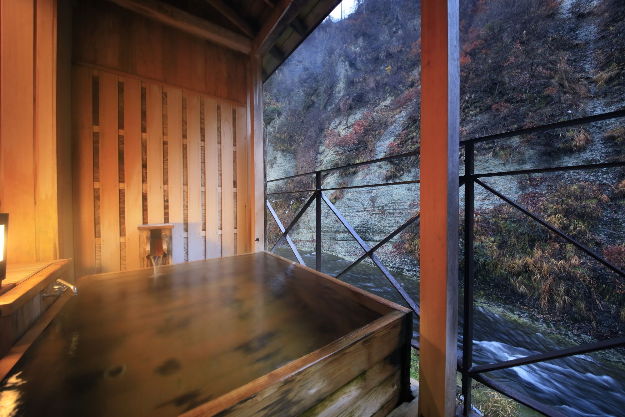 A wooden spa bath with a view of a forested hillside.