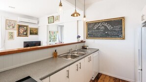 A kitchen with a chalkboard menu, a sink, and cabinets. - The Vintage Cottage (Waiheke Island)