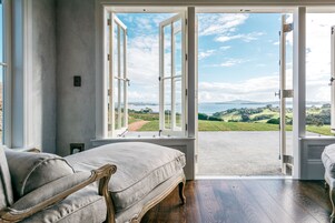 Um quarto com uma grande janela, um banco acolchoado e vista para uma paisagem verde.