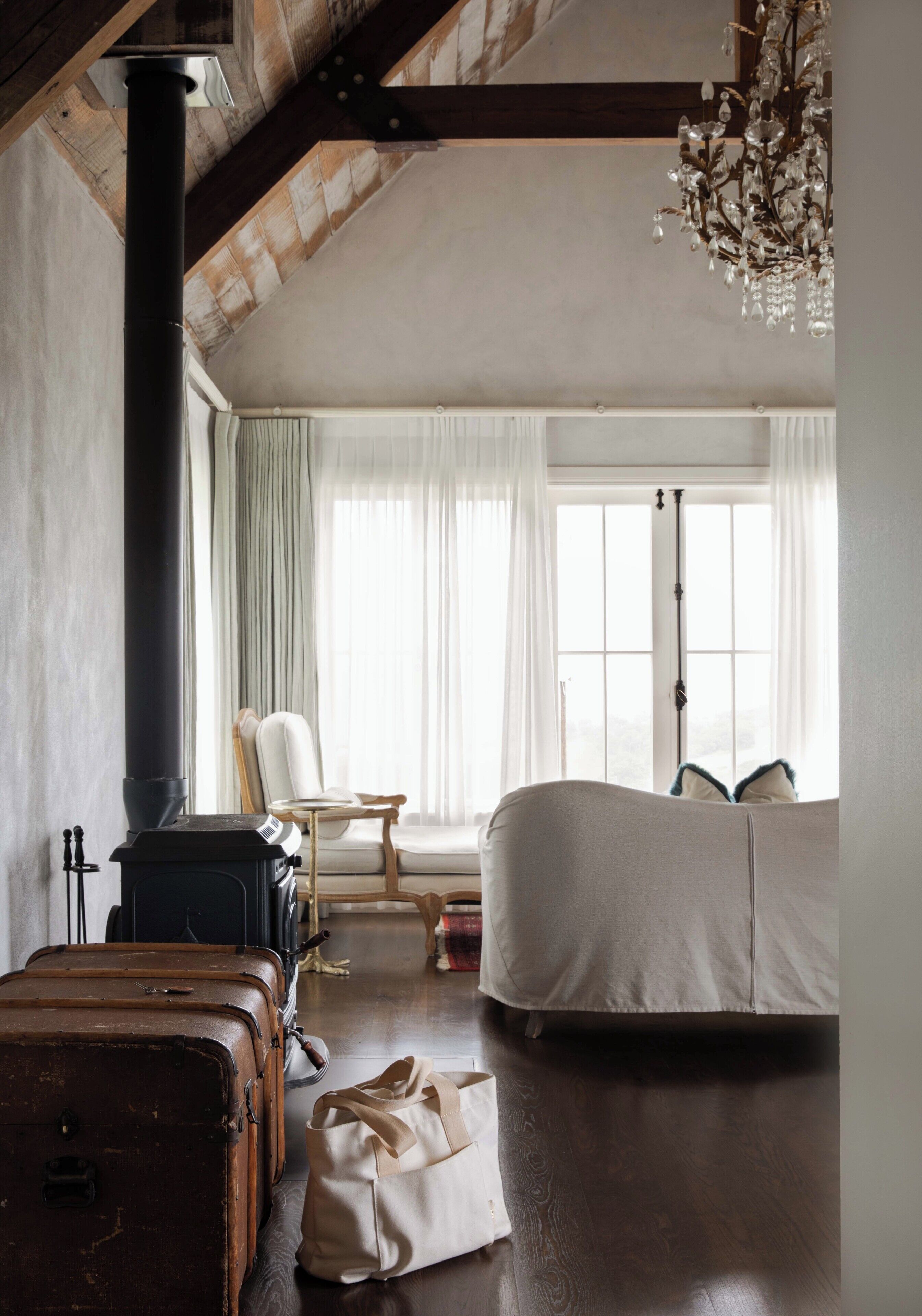 Una habitación con un ventanal grande, una silla, un sofá y una chimenea.