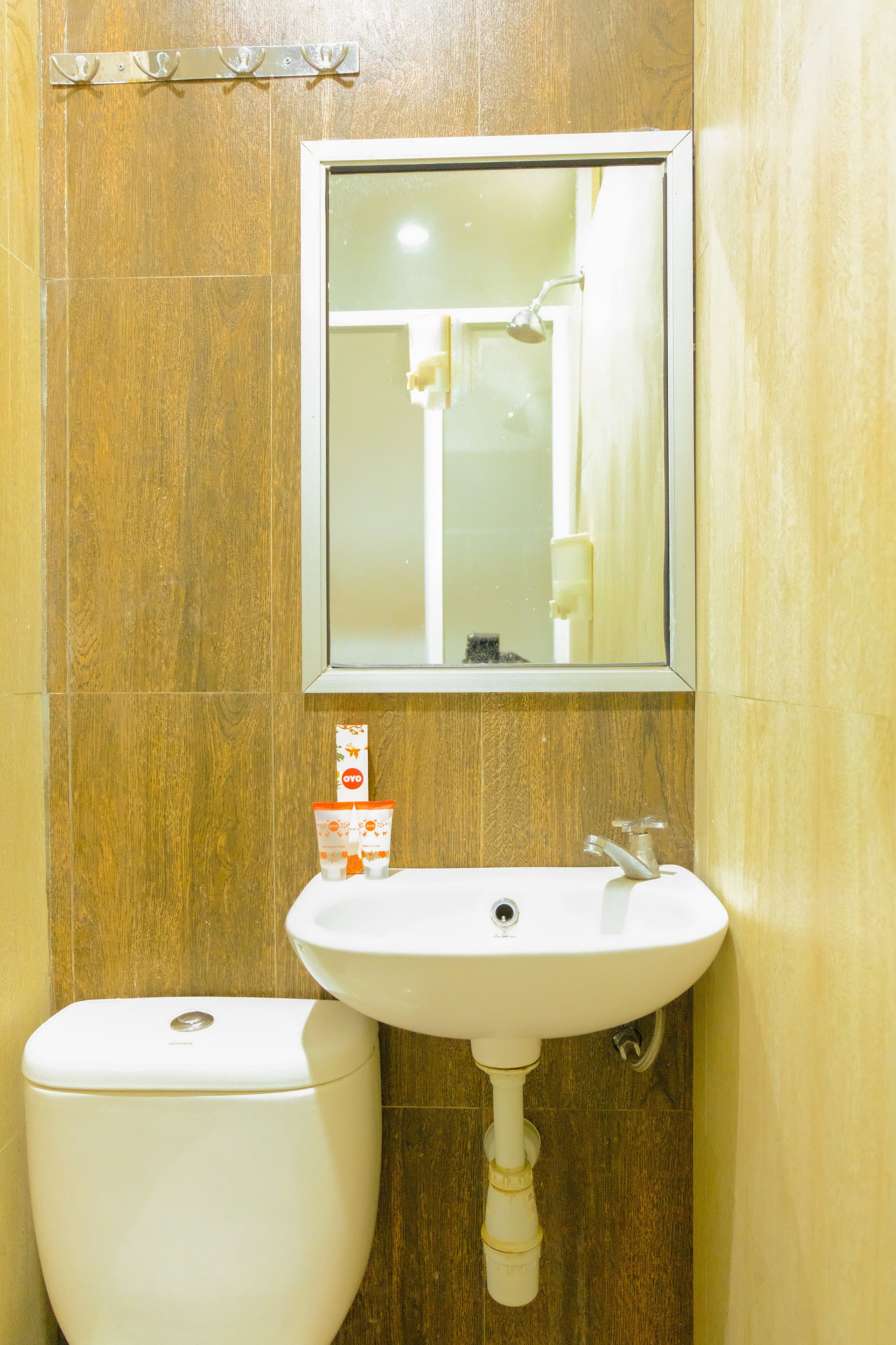 Un baño con lavamanos blanco, espejo y retrete.