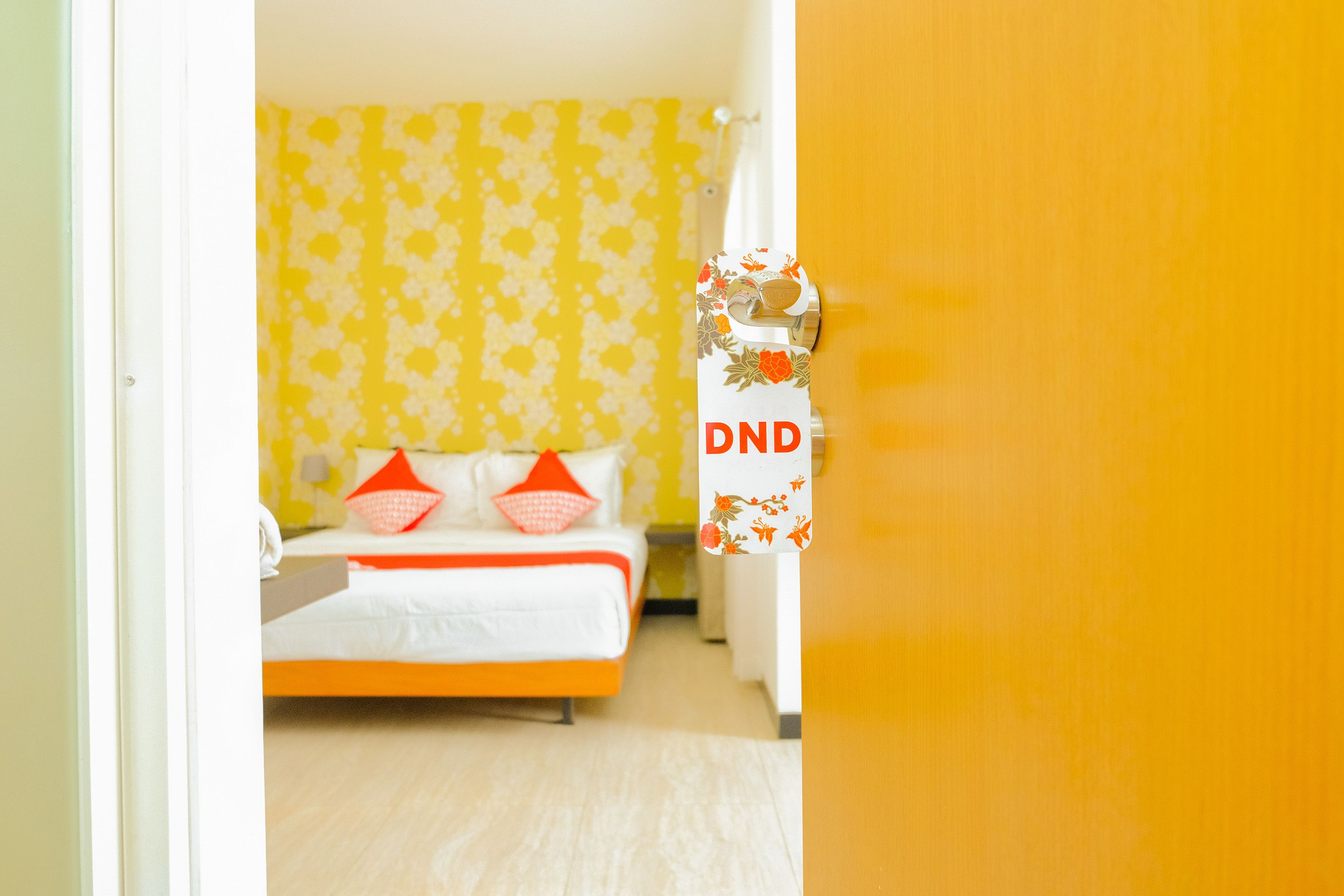 A room with a bed, a yellow patterned curtain, and a door with a DND sign.