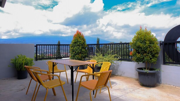 Une terrasse avec une table et des chaises, des plantes en pot et une vue sur le ciel et les nuages.