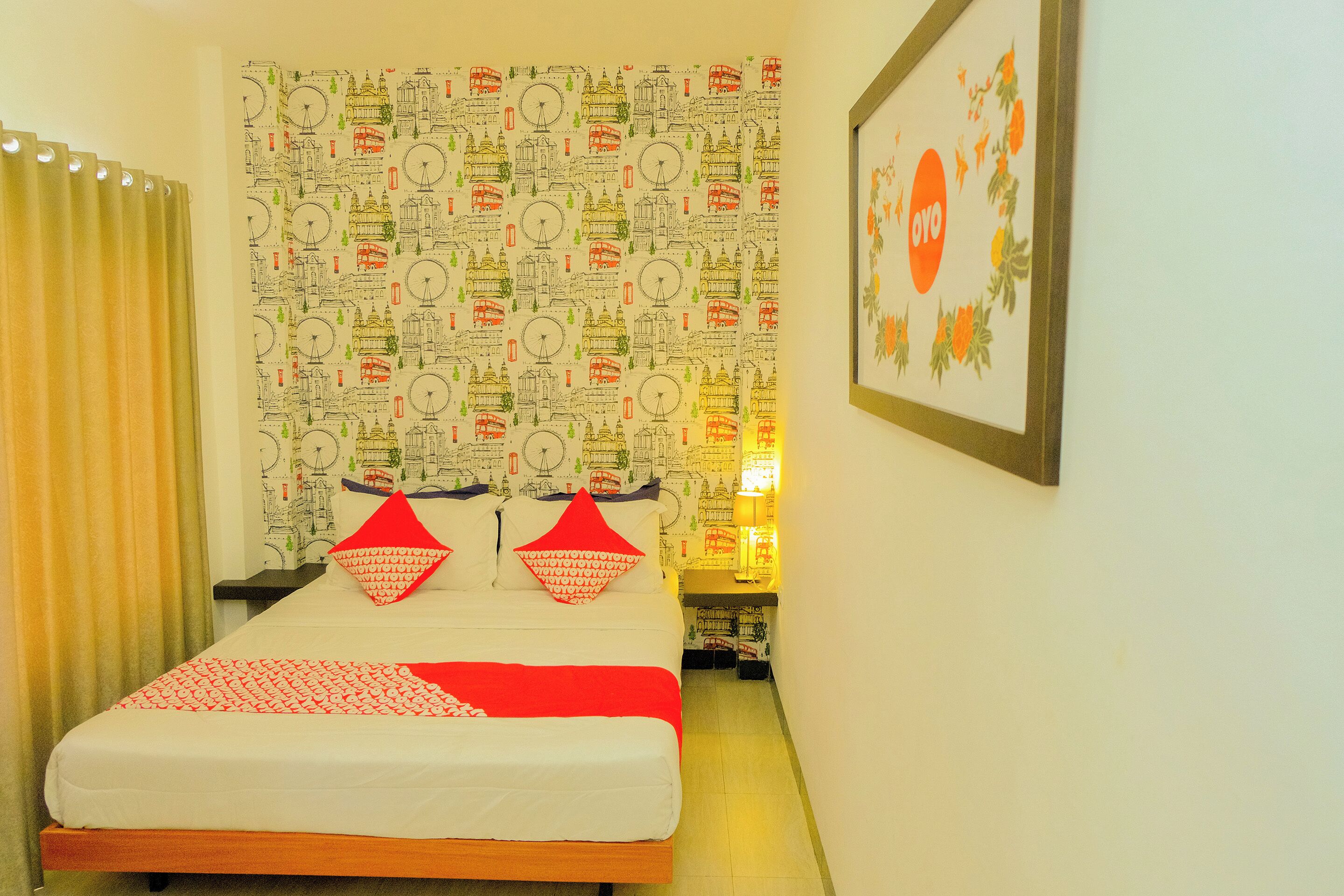 A room with a bed, a patterned wallpaper, a framed picture, and a curtain.