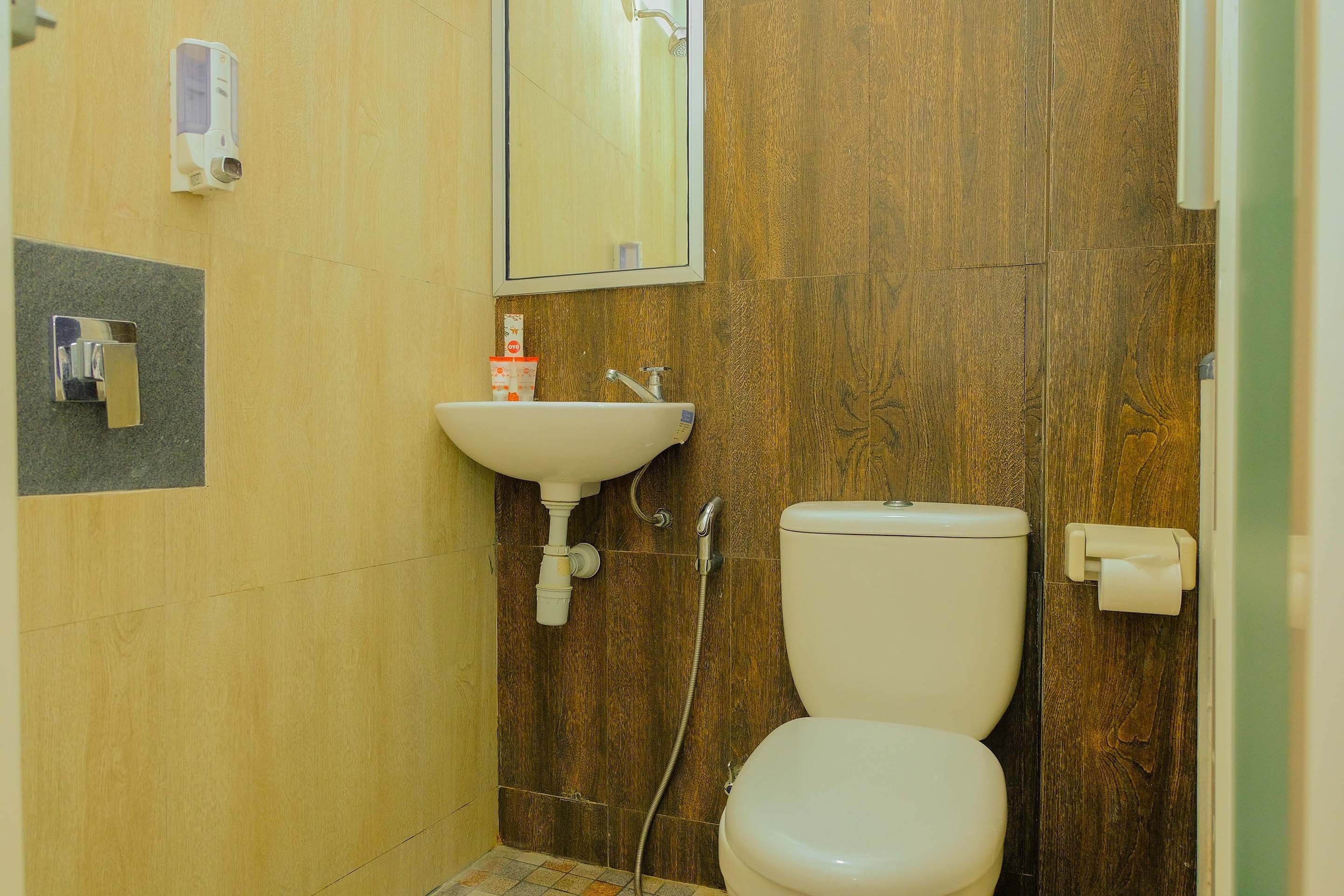 A bathroom with a wooden wall, a white sink, a toilet, and a mirror.