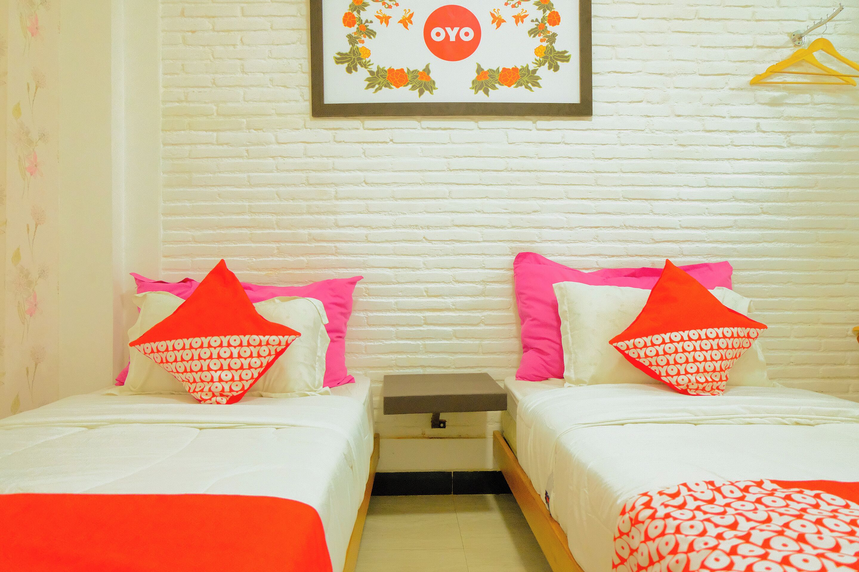 A hotel room with two beds, each with a pillow featuring a repeated pattern.