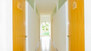 Un couloir avec les portes numérotées 35 et 32, qui mène à une pièce lumineuse dotée d’une fenêtre.