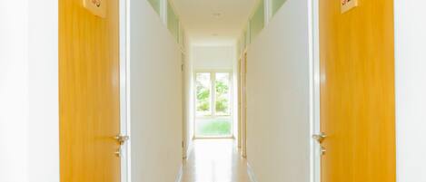 A hallway with doors numbered 35 and 32, leading to a bright room with a window.
