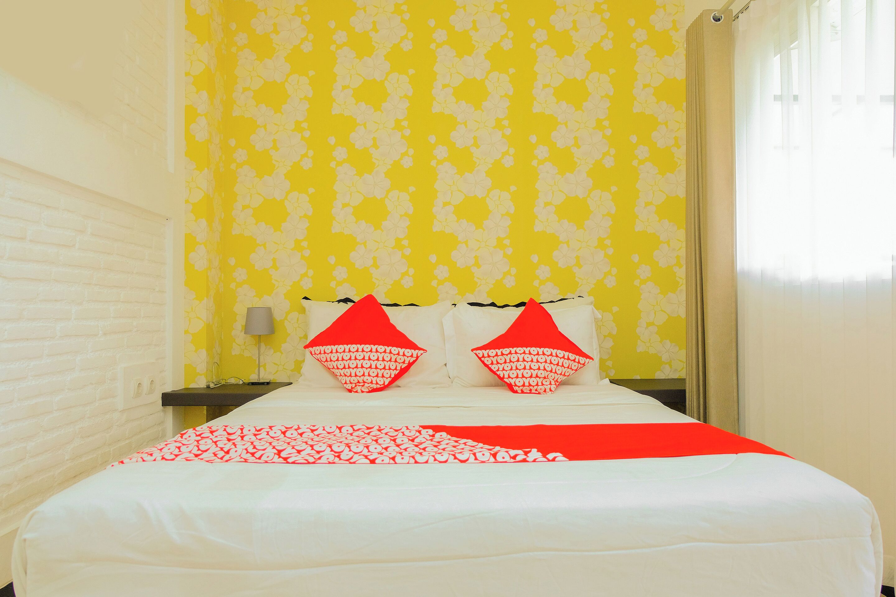 A hotel room with a bed, a nightstand, and a lamp.