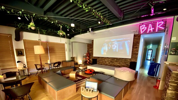 Ein moderner Loungebereich mit Bar, Sitzgelegenheiten und einer Projektionsleinwand.