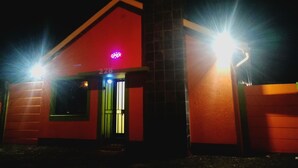 A building with a red facade, a visible entrance, and a neon 'OPEN' sign. - Luc Lodge (Cape Town)