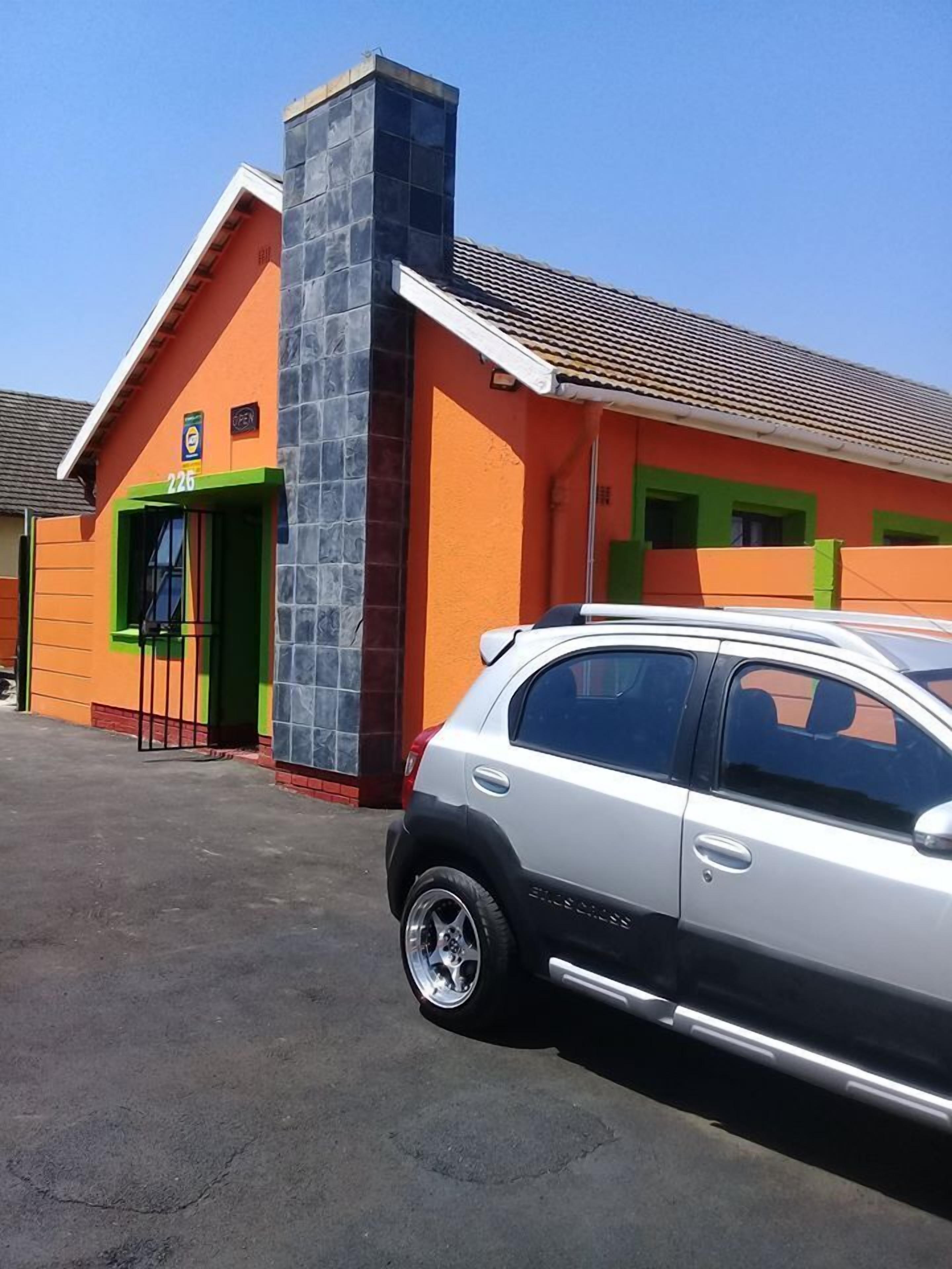 A building with a green door, a sign above it, and a parked car in front.
