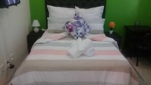A bed with striped bedding, a floral pillow, and a folded towel.