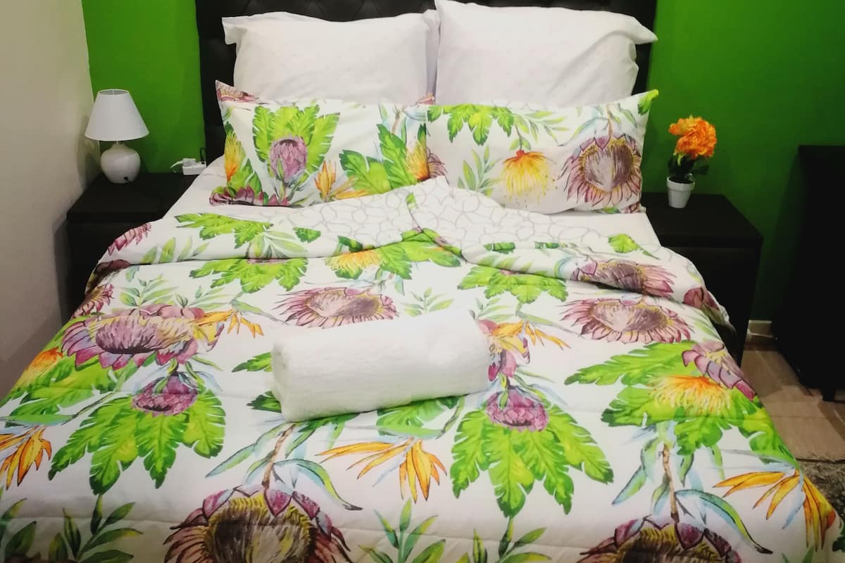 A bed with a floral bedspread, white pillows, and a black headboard.